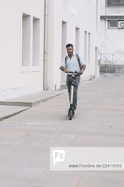 Casual businessman riding e-scooter in the city