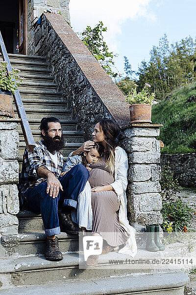 Family relaxing on stoop of a rustic house