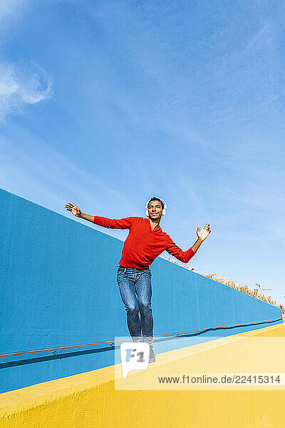 Young man with headphones  listening music  dancing on yellow wall