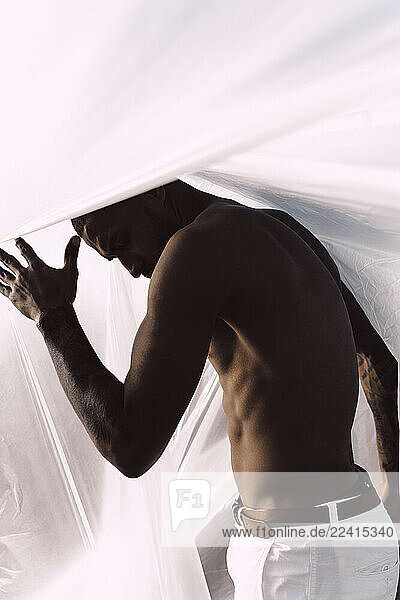 Barechested young man inside a plastic foil