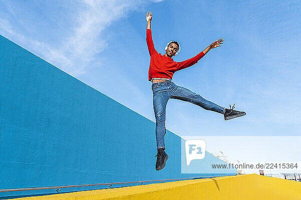 Young man with headphones  listening music  dancing on yellow wall