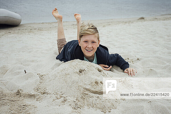 Portrait of happy blond boy with freckles wearing hooded jacket in front of Zeya River  Russia