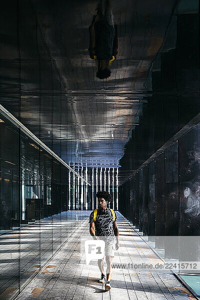 Man with yellow backpack walking through a passage  Barcelona  Spain