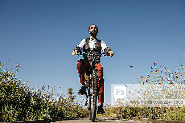 Well dressed man with his bike on a wooden walkway in the countryside after work