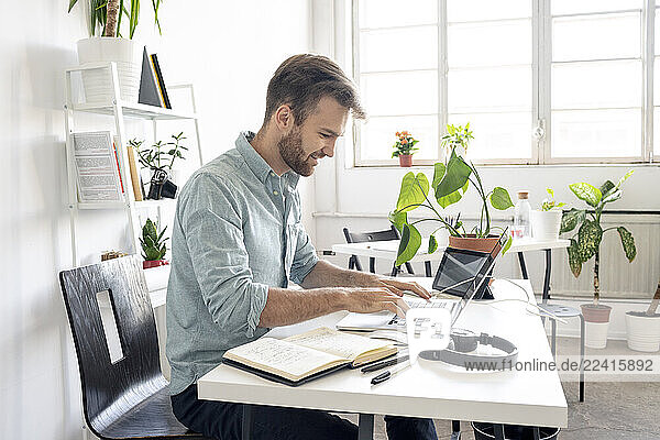 Smiling man using laptop at desk in office
