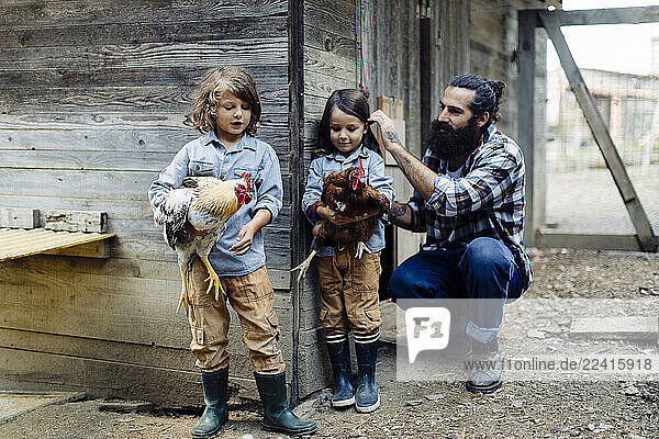 Father with two kids in chicken coop on an organic farm