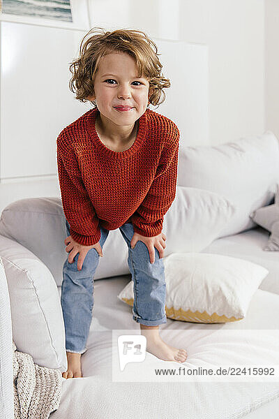 Portrait of smiling girl standing on couch at home