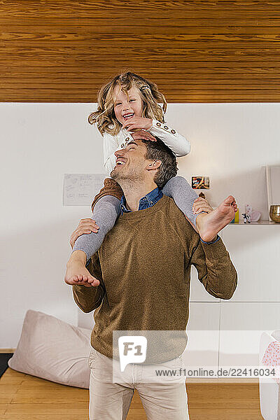 Happy father carrying daughter on shoulders at home