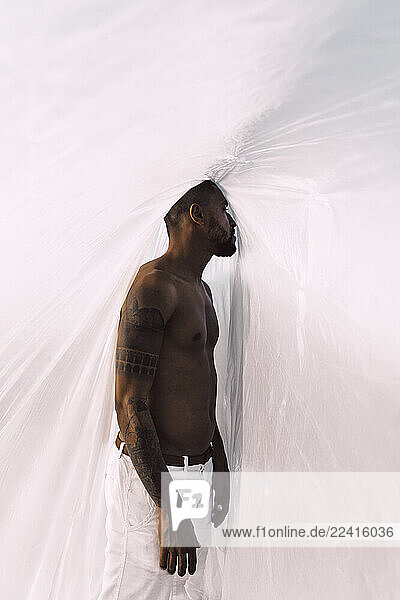 Barechested young man inside a plastic foil