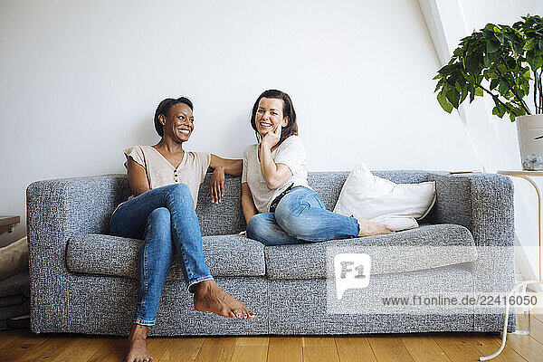 Two smiling women sitting on couch at home
