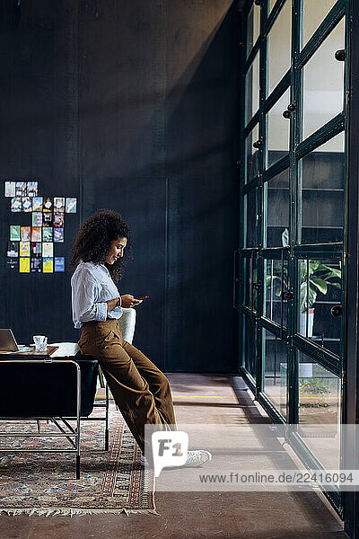 Young businesswoman using smartphone in loft office