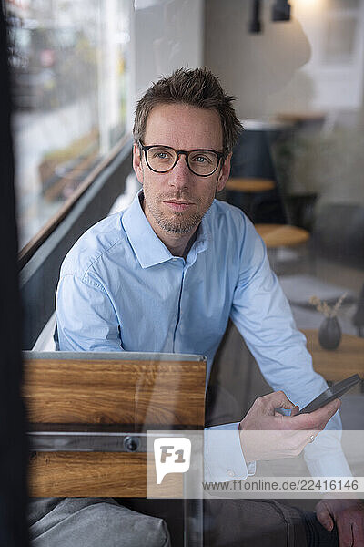 Businessman in a café working remotely with a smartphone