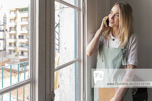 Young woman on the phone looking out of window