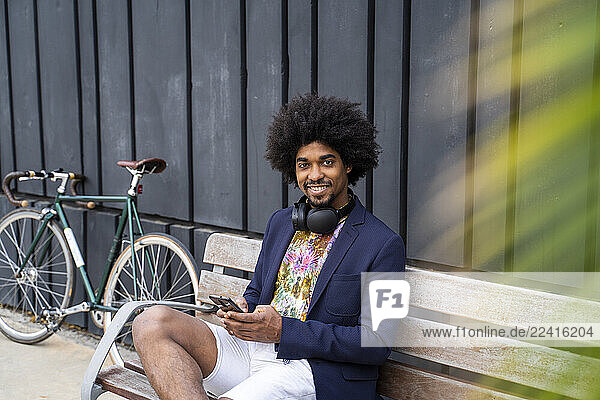 Portrait of stylish man with cell phone sitting on a bench