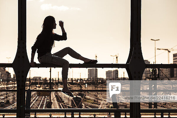 Young woman sitting on Hacker bridge at sunset  Munich  Germany
