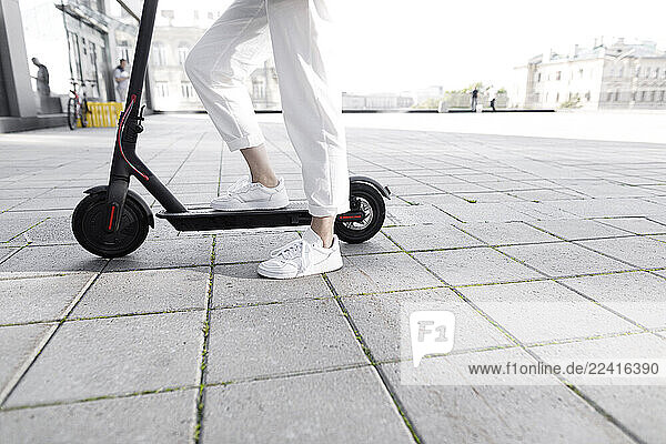 Young woman with e-scooter  modern buildings in the background