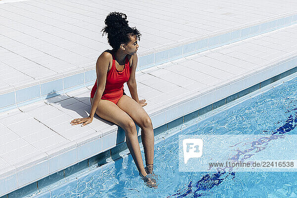Young woman wearing red swimsuit relaxing at poolside