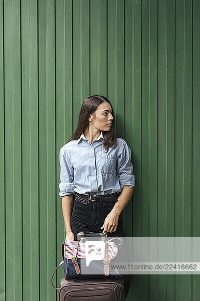 Young traveller leaning on green wall at station