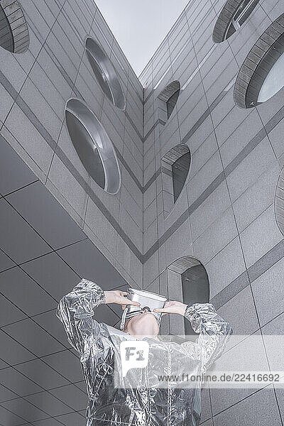Girl in silver suit. looking through VR goggles in futuristic city