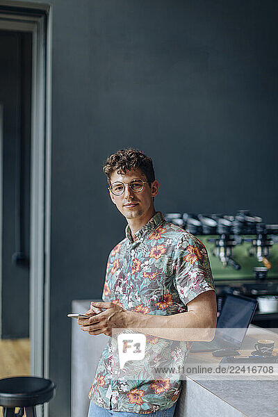 Young man standing in cafe  using smartphone
