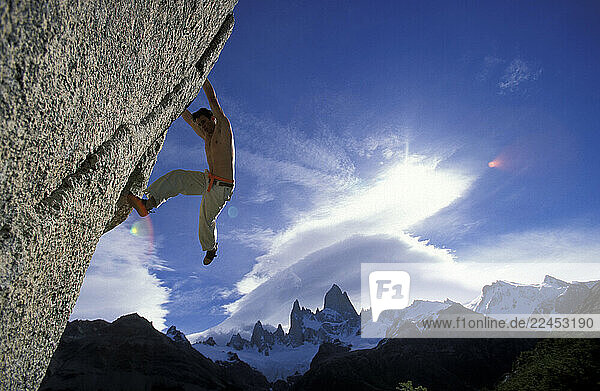 A male climber on an overhanging bouldering route.
