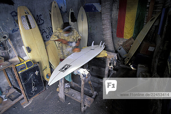 A man shaping a surfboard in a shop.