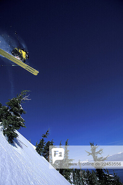 A male alpine skier jumps off a cliff in the backcountry.