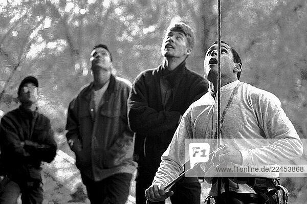 A man belaying with a group of friends looking on.