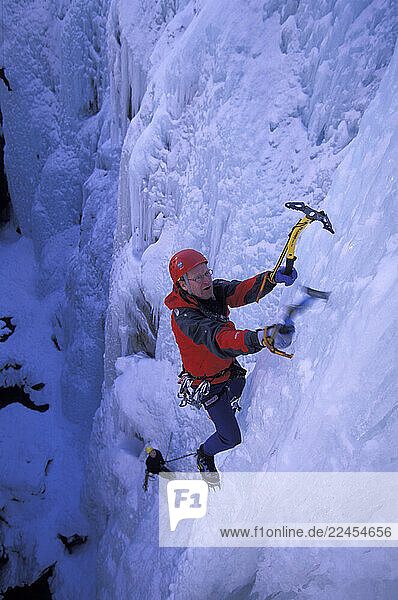 A man ice climbing a frozen waterfall.