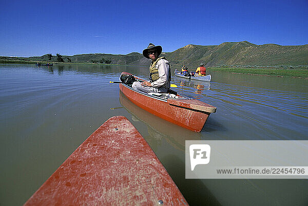 A group of men and boys canoeing on the river on a sunny day.