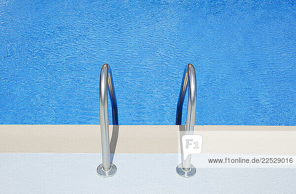 Swimming pool ladder railings and blue water