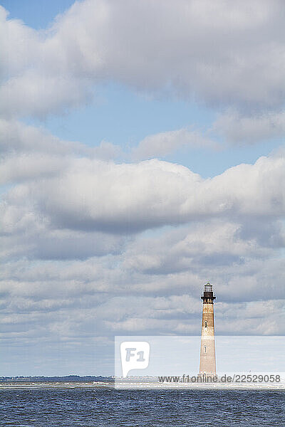 White puffy clouds above Morris Island Light