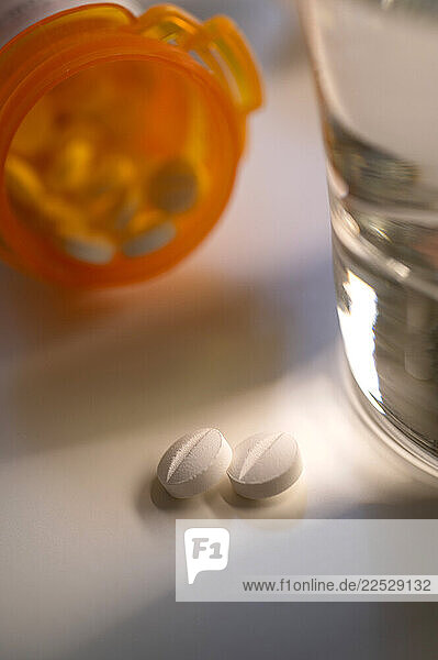 Two pills spilling out of pill bottle