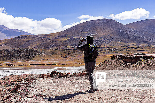Rear view of woman photographing barren landscape in Atacama Desert
