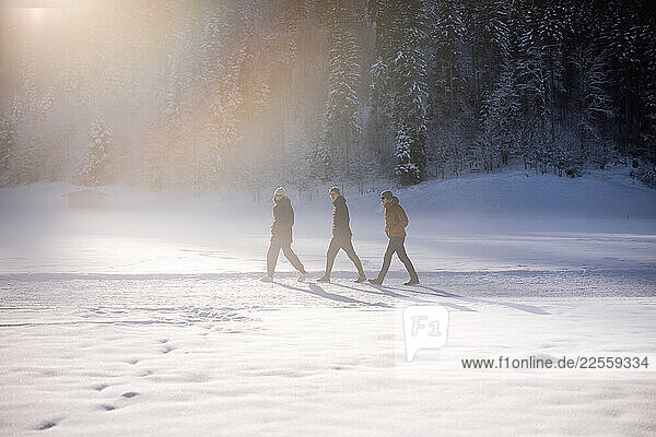 Three people walk through misty snow in Kirchberg  Tyrol