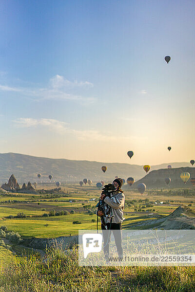 Tourist hugging her dog with hot air balloons flying over Cappad