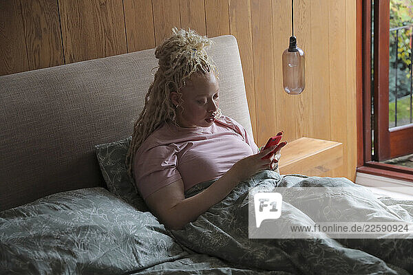 Woman with smart phone in bed