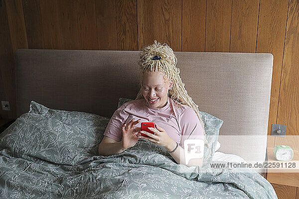 Woman with smart phone in bed