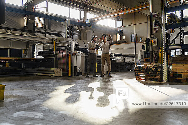 Business people with digital tablet standing at factory