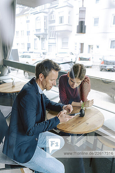 Two people having a business discussion in a café using a smartphone