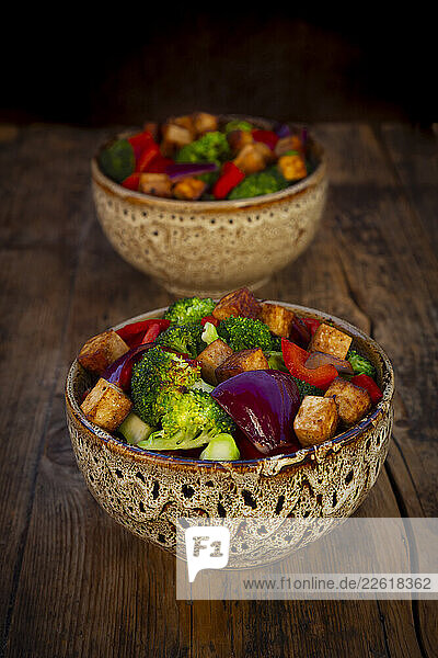 Vegan tofu and vegetable bowls on a rustic wooden table