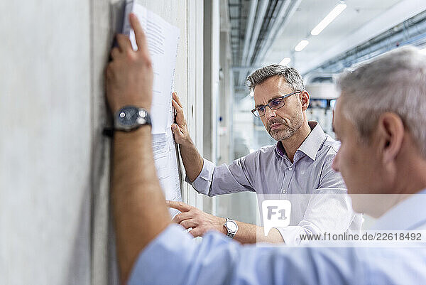 Business professionals discussing plans in a production hall