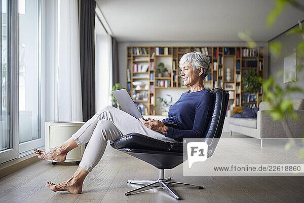 Woman relaxing at home using a laptop in a modern living room