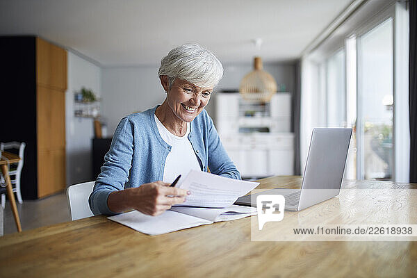 Woman working on a laptop at home in a bright kitchen