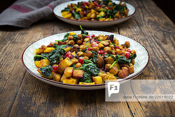Crispy potato  chickpeas  spinach  and pomegranate seeds on a dark wooden table