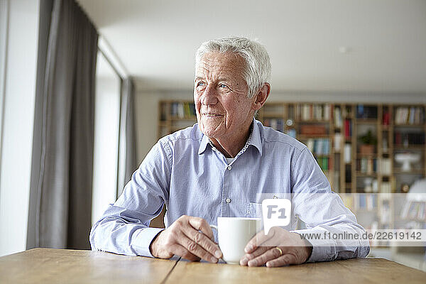 Senior man enjoying a cup of coffee at home with a thoughtful expression