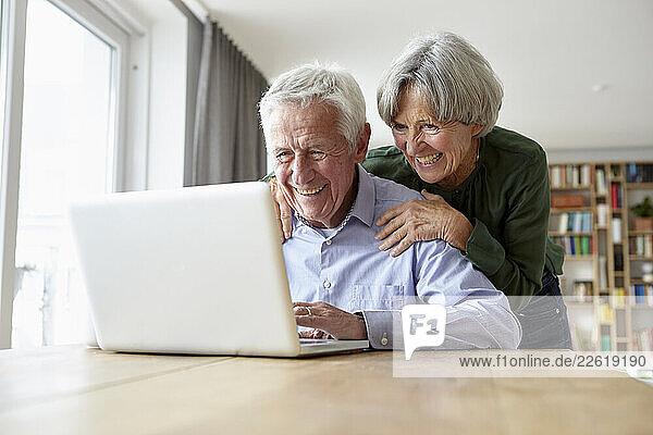 Senior couple enjoying time together using a laptop at home