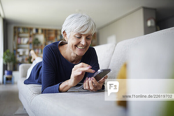 Senior woman smiling while using a tablet at home