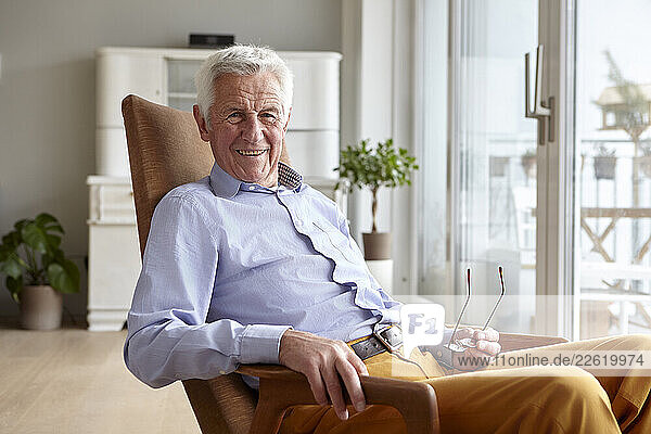 Senior man sitting in a chair at home  smiling and enjoying his day