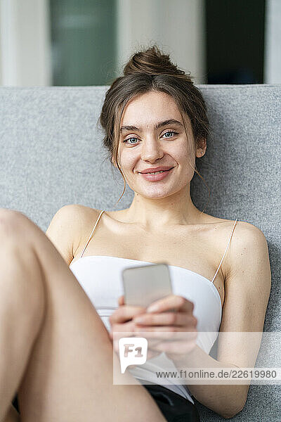 Woman relaxing at home with smartphone in a cosy loft apartment